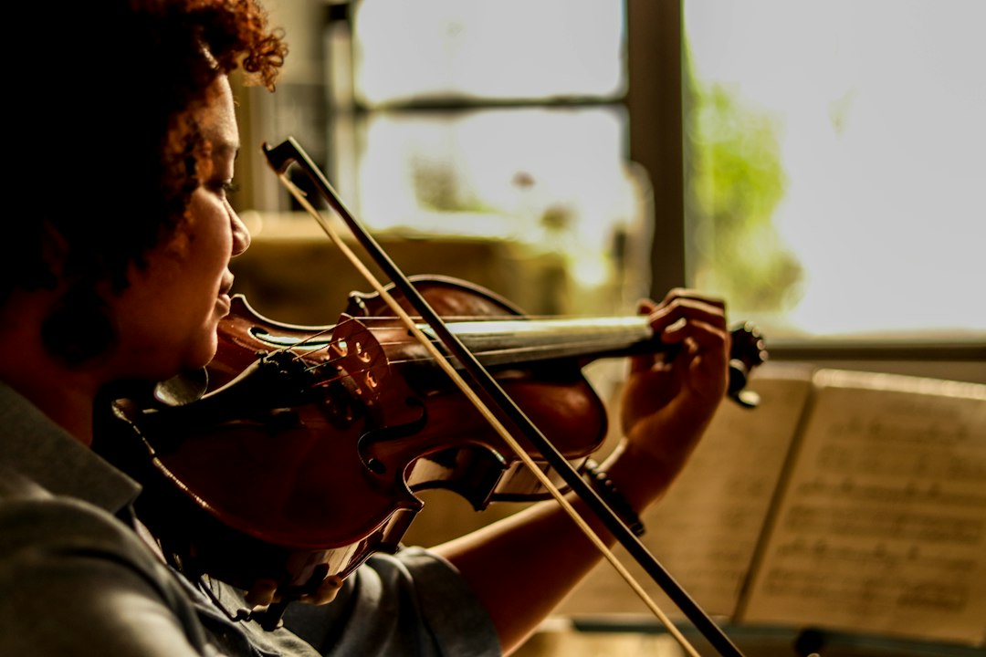Child practising violin during a music class, a creative after-school activities option