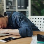 Office worker showing signs of mid-career burnout at her desk
