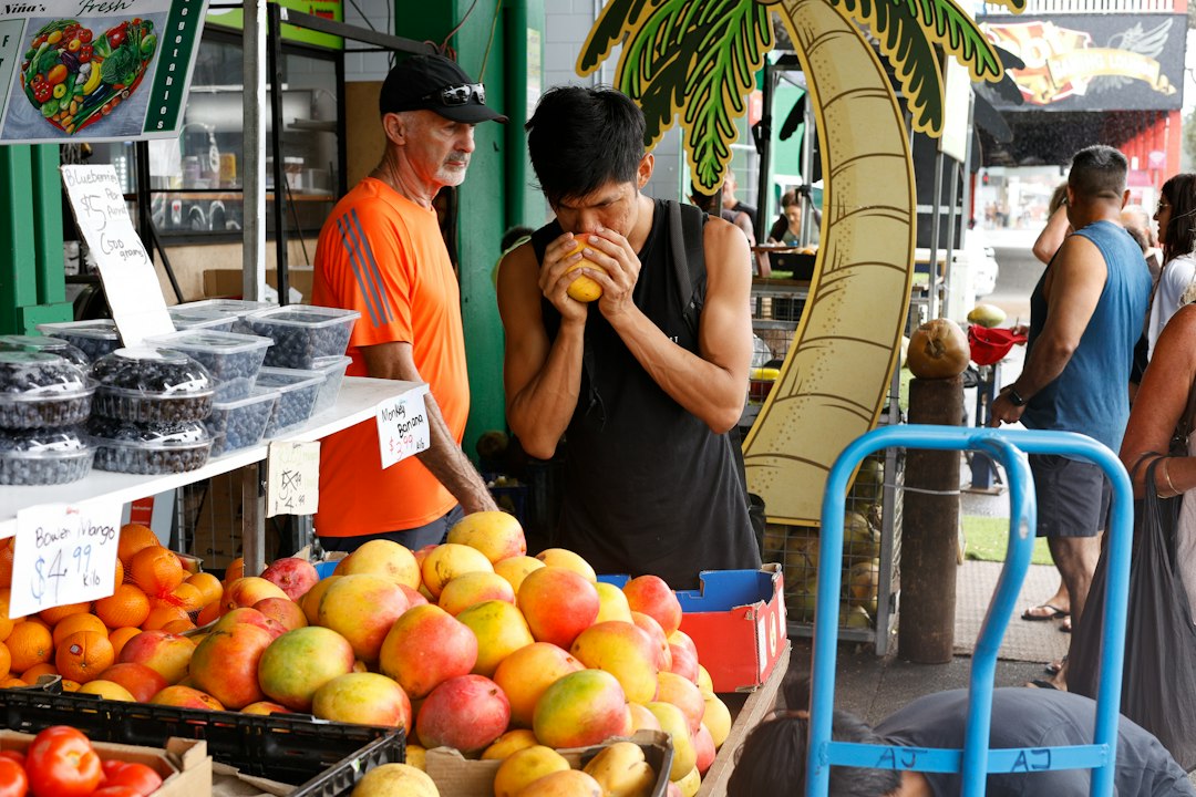 Shopper checking a ripe mango for softness at a Sydney market stall